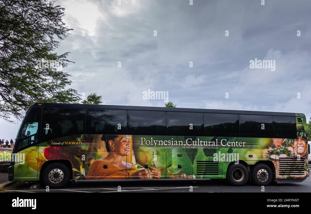 Oahu, Hawaii, USA. - 11. Januar 2020: Öffentlicher Reisebus mit farbenfroher Werbung auf der Seite, die Frau und Mann zeigt, viel Grün unter schwer Stockfoto