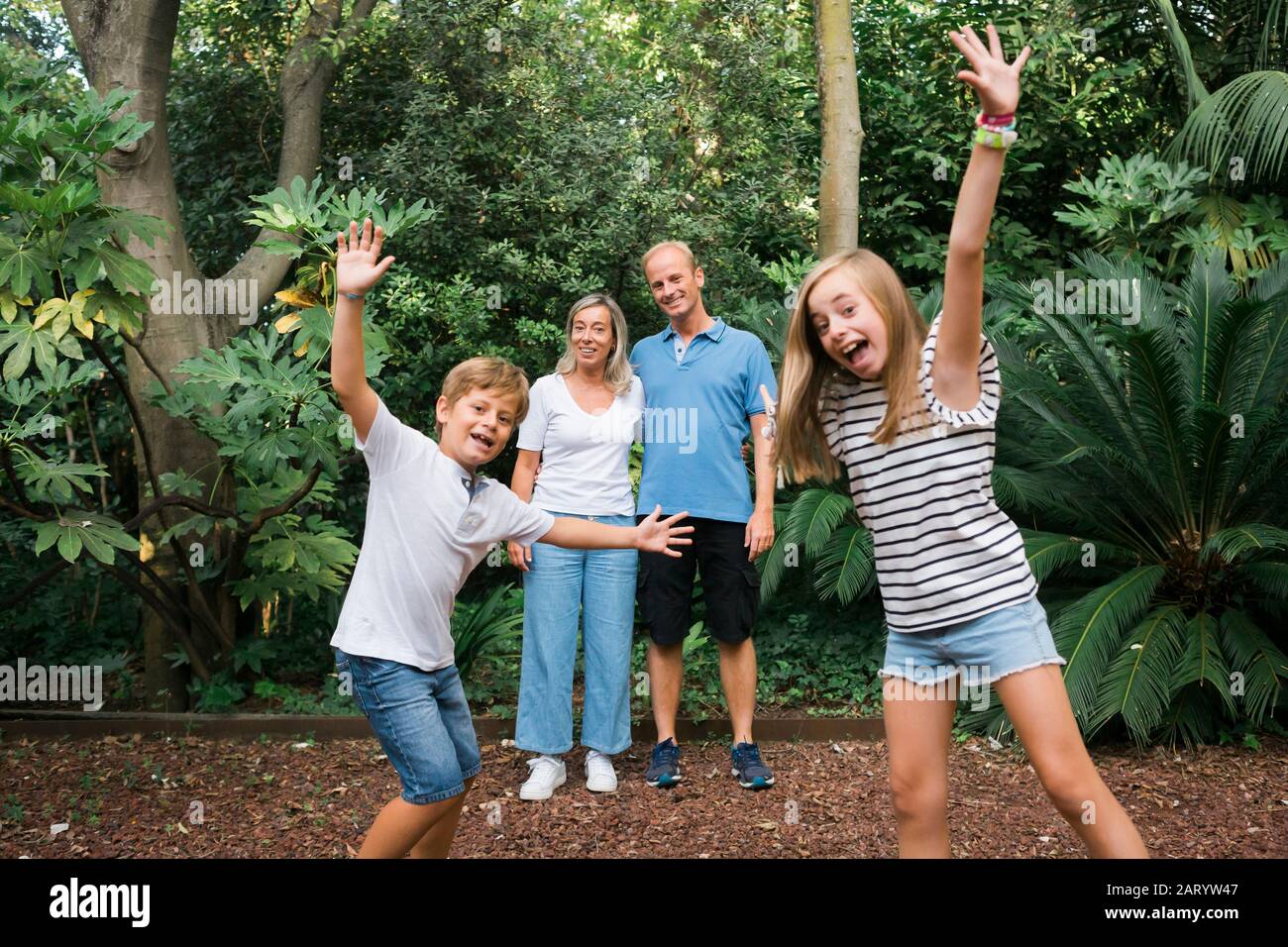 Kinder posieren vor den Eltern am Busch Stockfoto