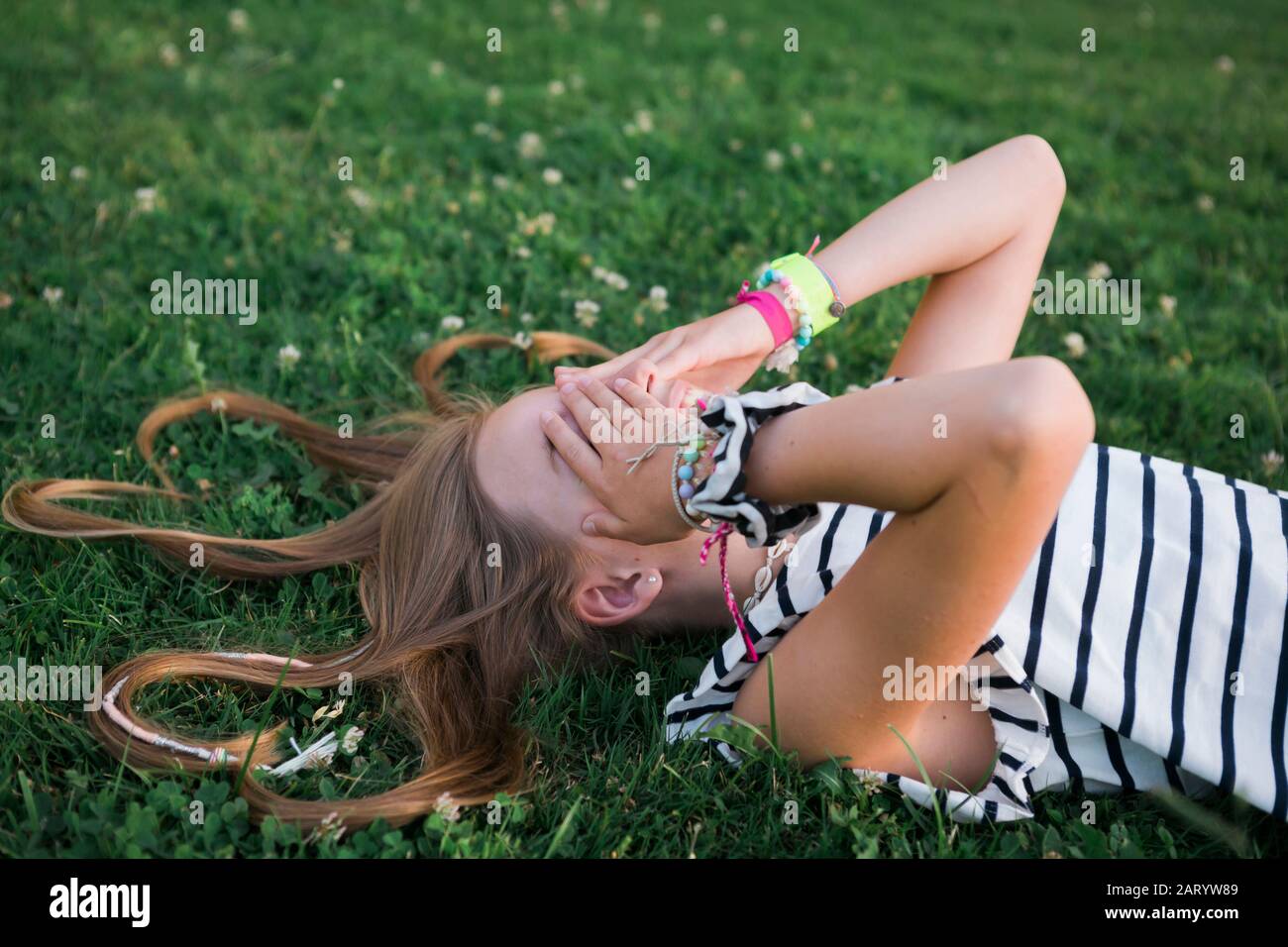 Mädchen bedeckt ihre Augen auf Gras liegen Stockfoto