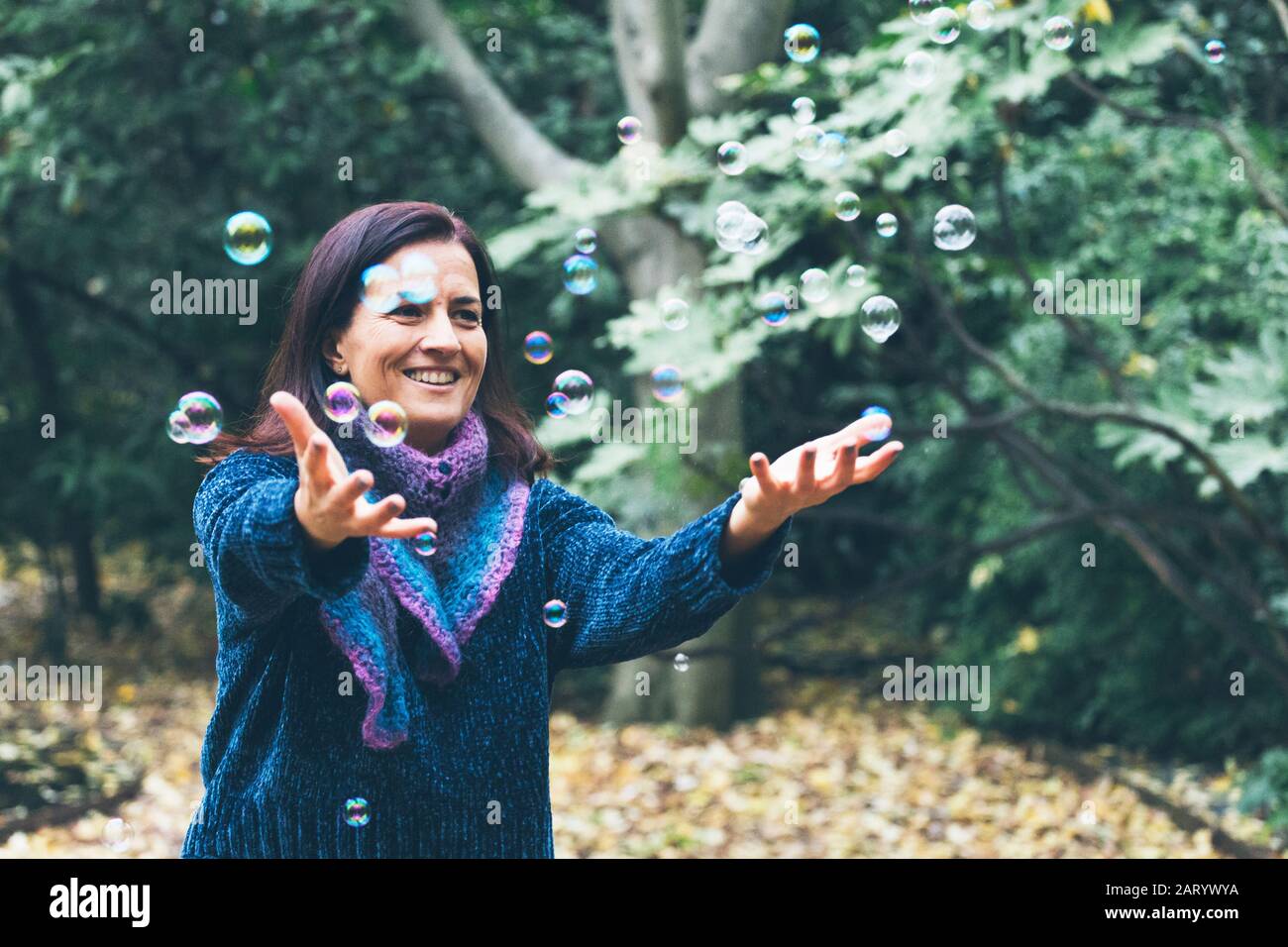 Lächelnde Frau spielt mit Blasen Stockfoto