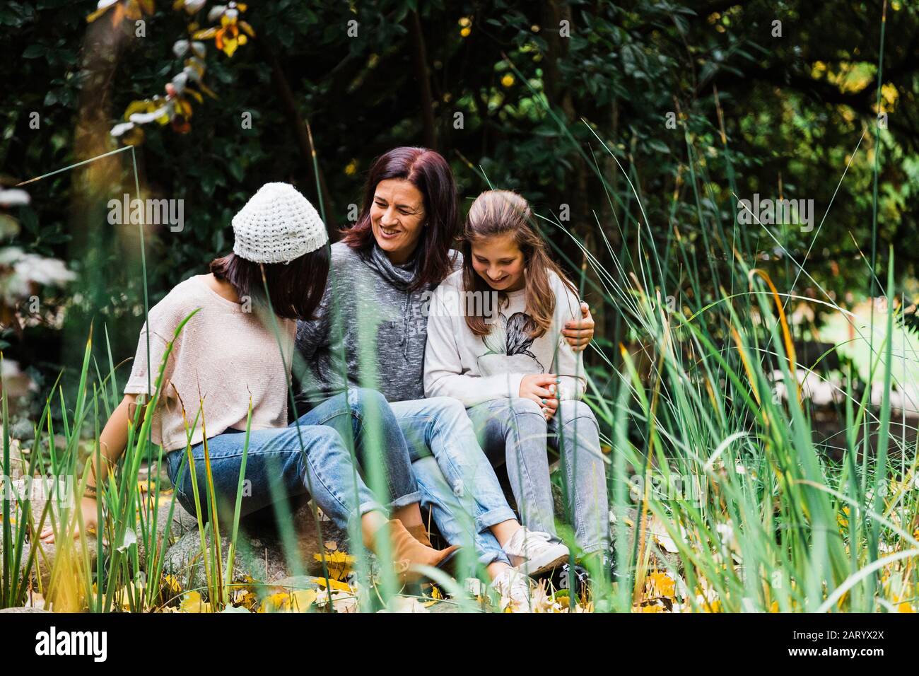 Mutter und Töchter umarmen auf Gras Stockfoto