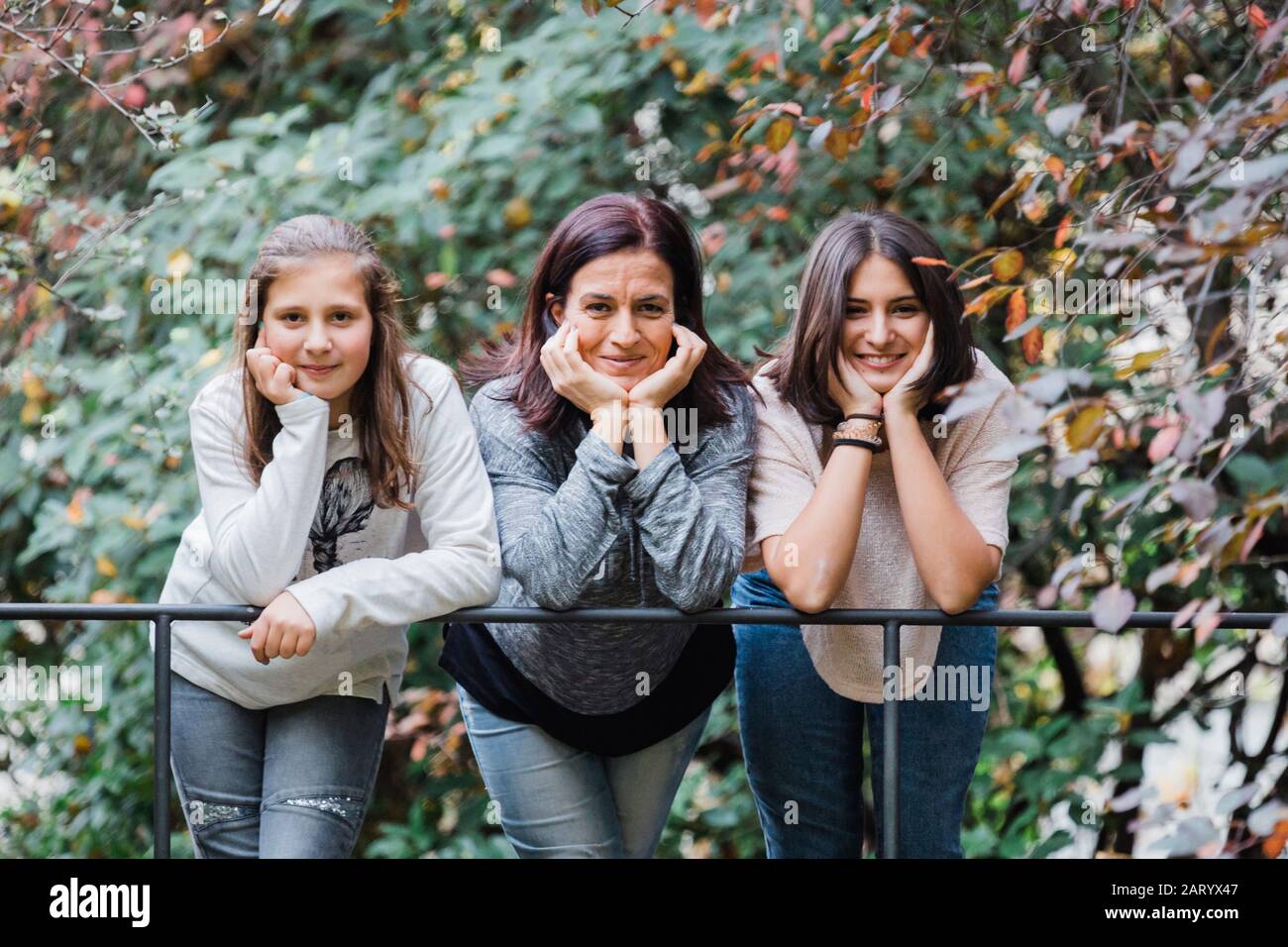 Mutter und Töchter lächeln und lehnen sich an Geländer Stockfoto
