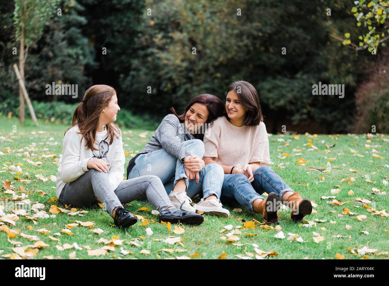 Mutter und Töchter sitzen auf Rasen Stockfoto