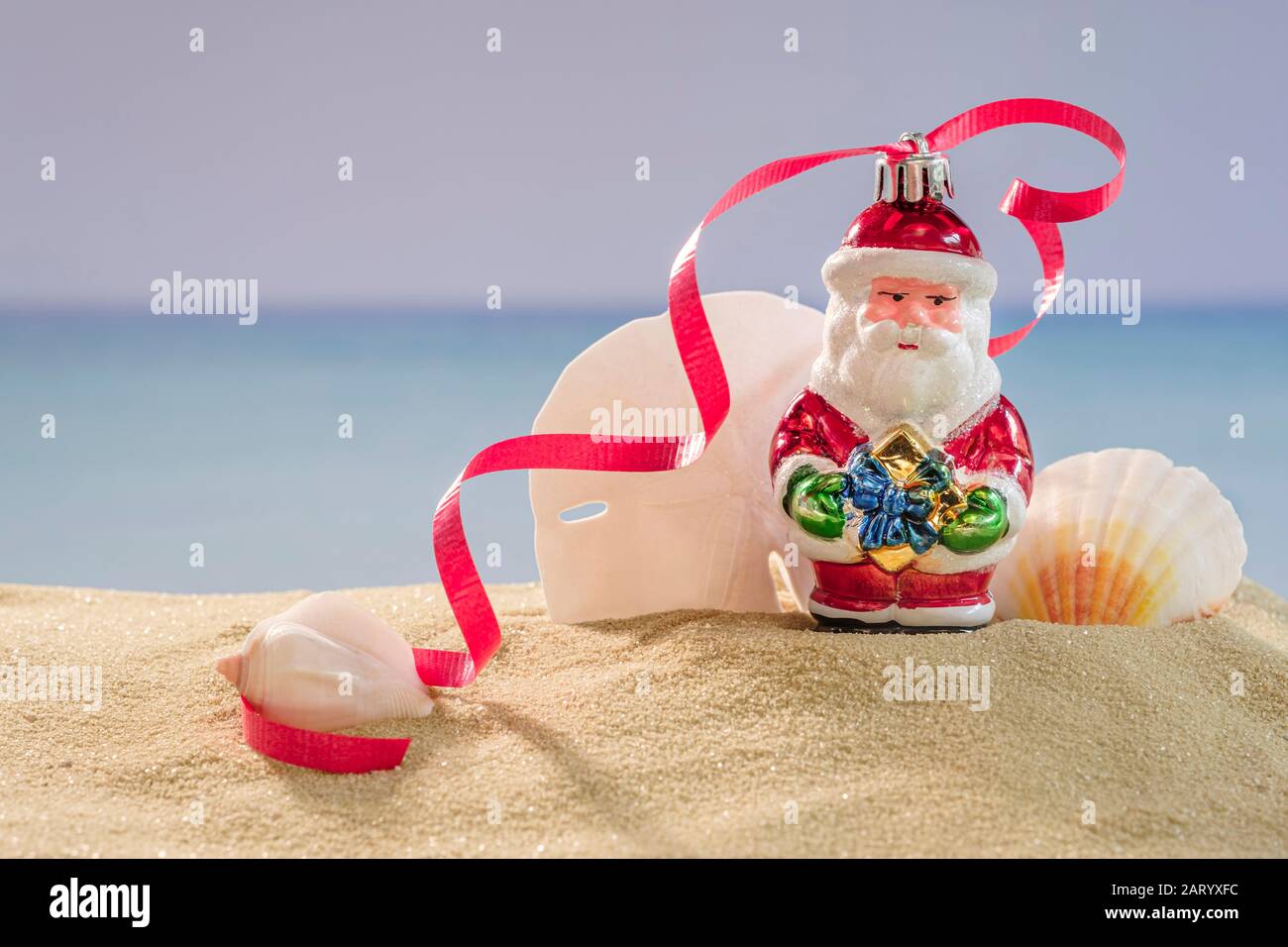 Weihnachtsmann Dekoration und Muscheln auf Sand Stockfoto