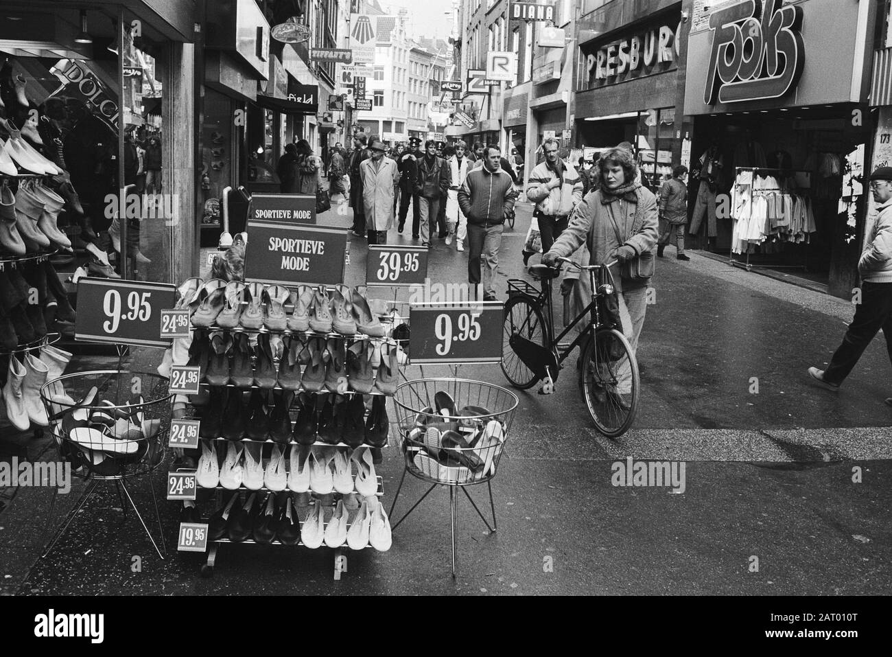 Kalverstraat mit Shoppingshowings Frau mit Fahrradbetrachtung vor einem Laden zeigte Schuhe Datum: 1. März 1983 Ort: Amsterdam, Noord-Holland Schlagwörter: Schuhe, Geschäfte Stockfoto