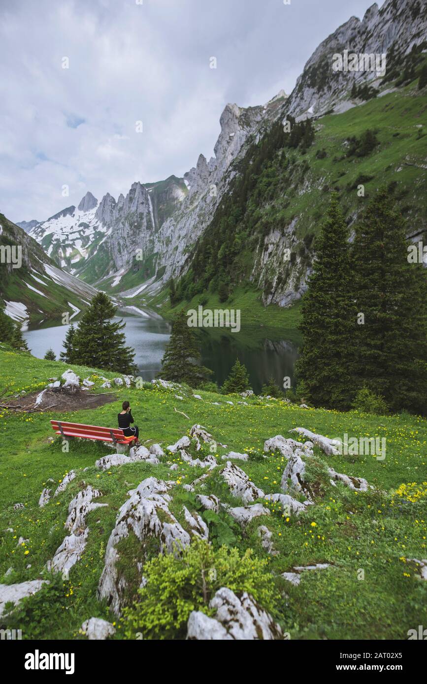 Frau sitzt auf einer Bank bei Bergen in Appenzell, Schweiz Stockfoto