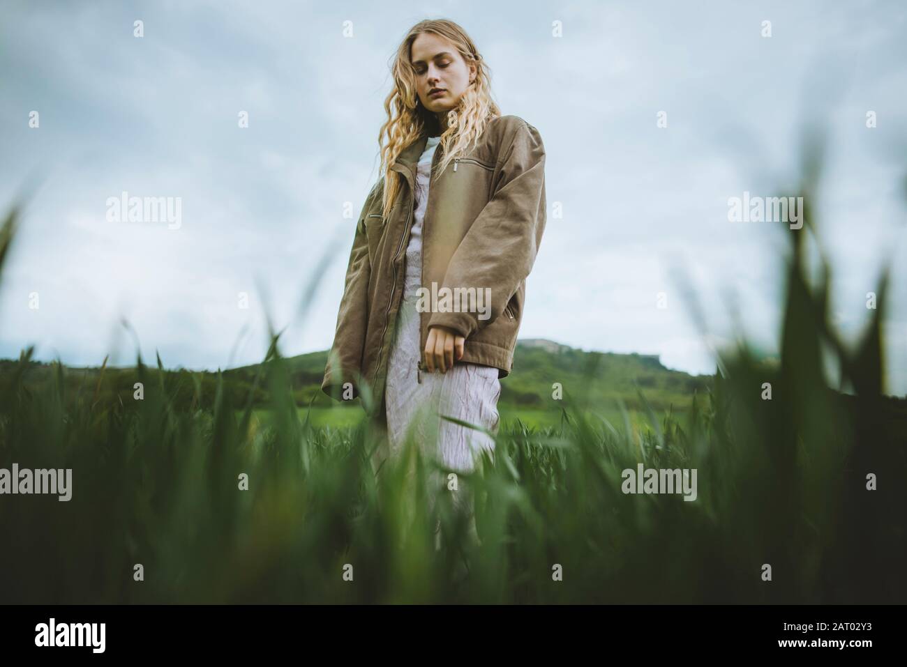 Frau trägt Jacke hinter Gras Stockfoto