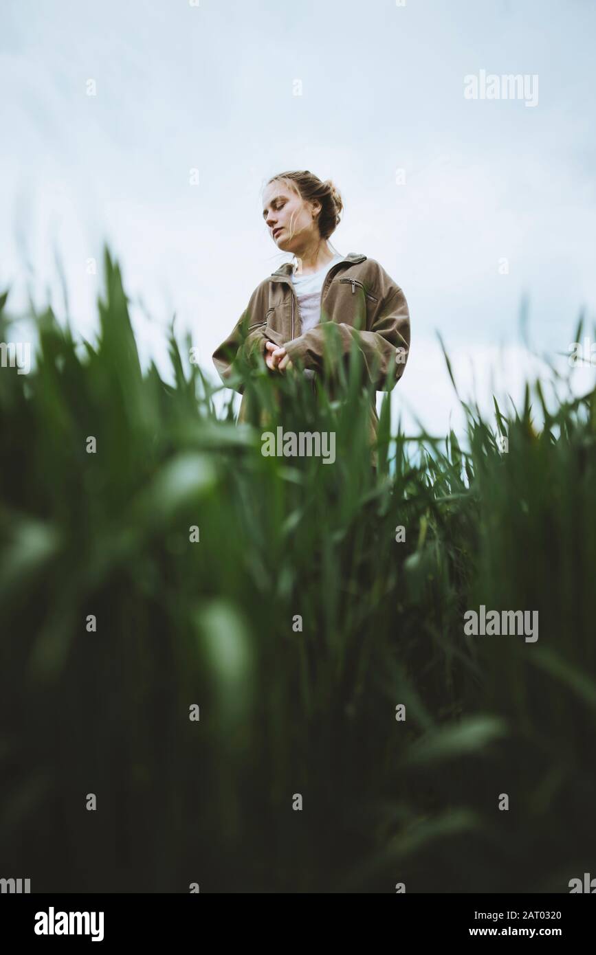 Frau trägt Jacke hinter Gras Stockfoto