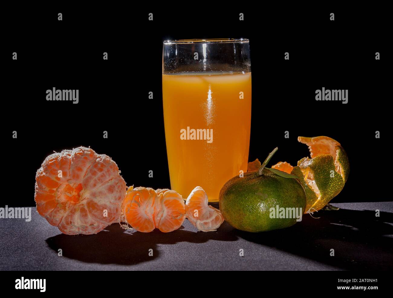 Orangen Tangerin und Glas, Zitrusreticula. Auf dem Tisch mit schwarzem Hintergrund und Hintergrundbeleuchtung Stillleben .Mandarinsorte Orange enthält pomelo und c V Stockfoto