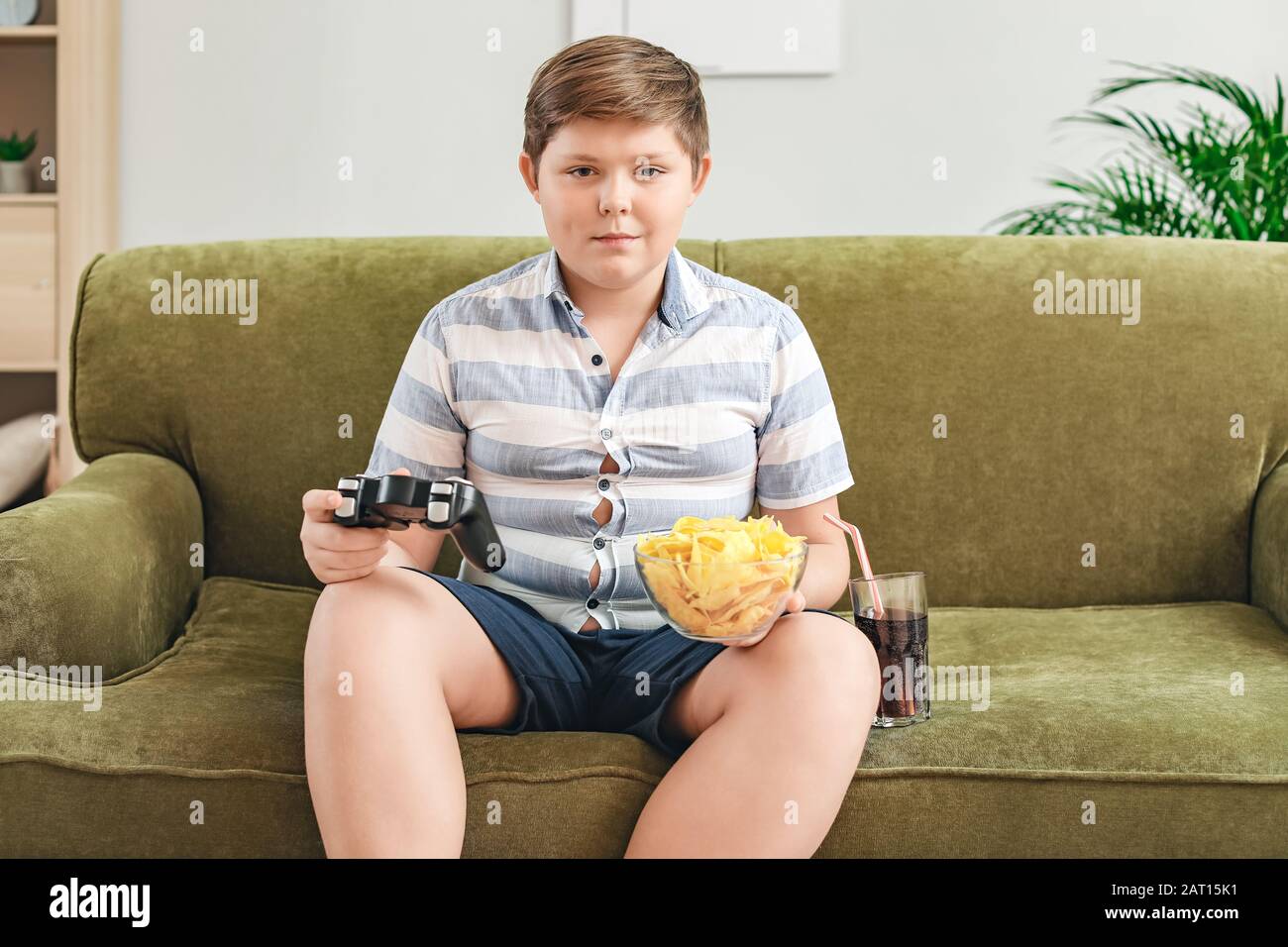 Übergewichtiger Junge mit Chips, der zu Hause Videospiel spielt Stockfoto