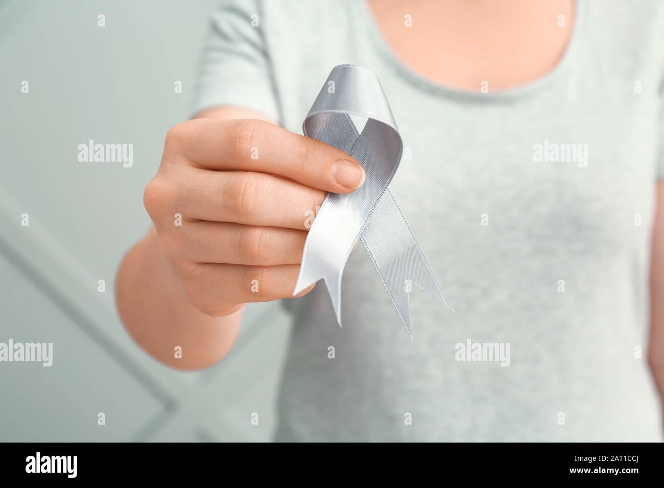 Frau mit Parkinson-Bewusstseinsband auf grauem Hintergrund, Nahaufnahme Stockfoto