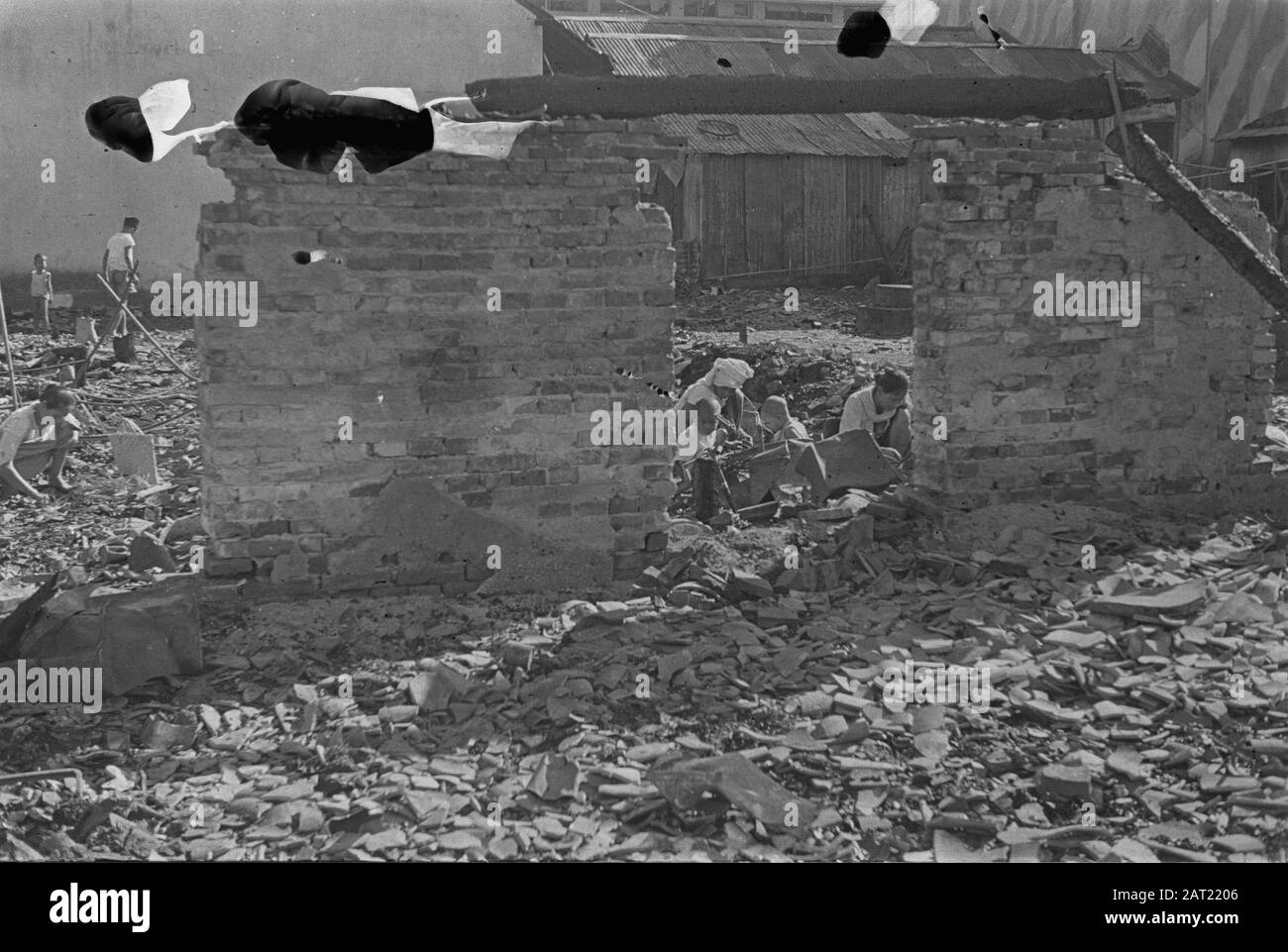 Fotoreportage Palembangs Familie durchsucht die Trümmer eines zerstörten Gebäudes Datum: Januar 1947 Ort: Indonesien, Niederländische Ostindien, Palembangs, Sumatra Stockfoto