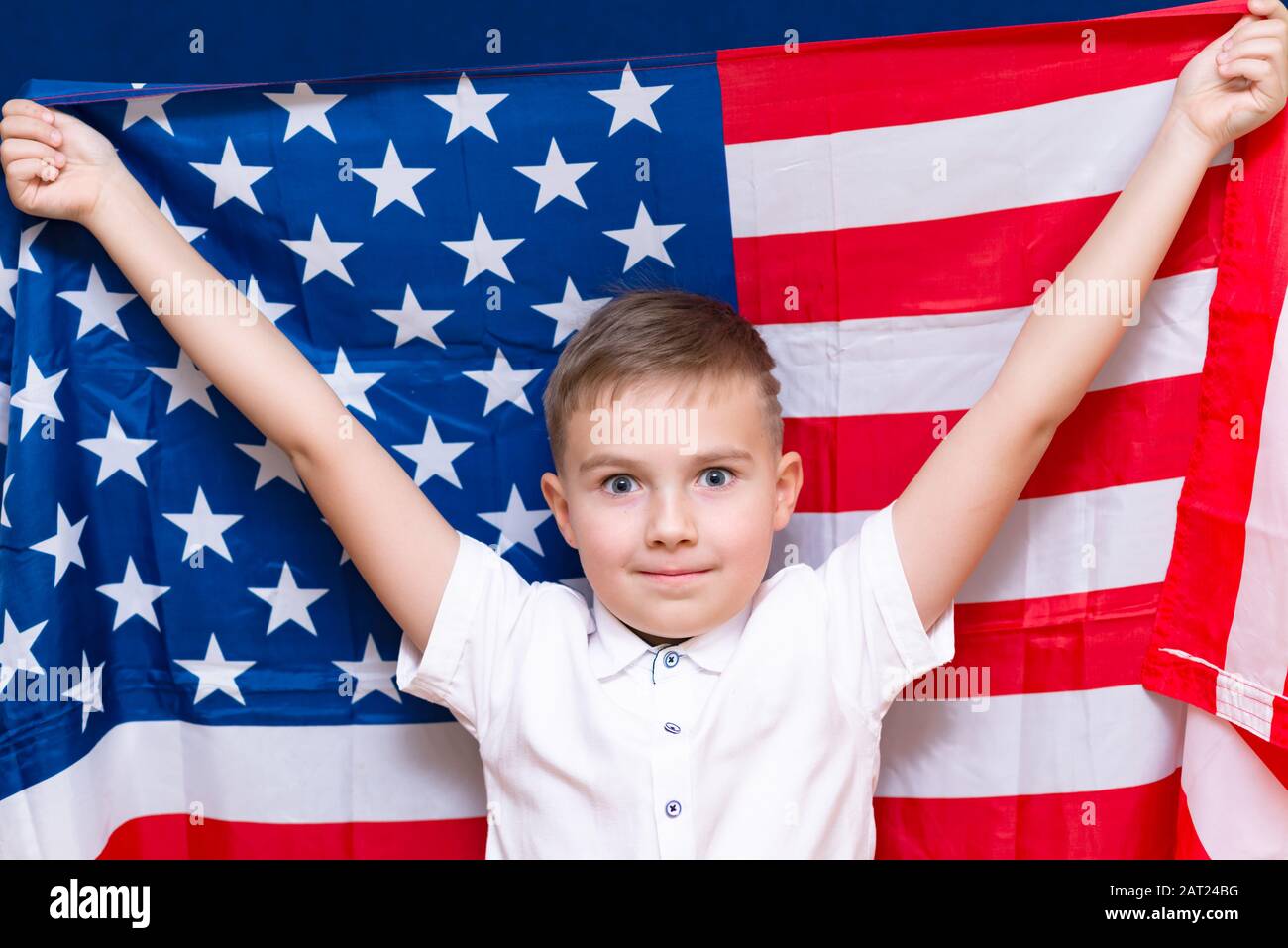 Boy hält eine USA-Flagge über blauem Studiohintergrund. Stockfoto