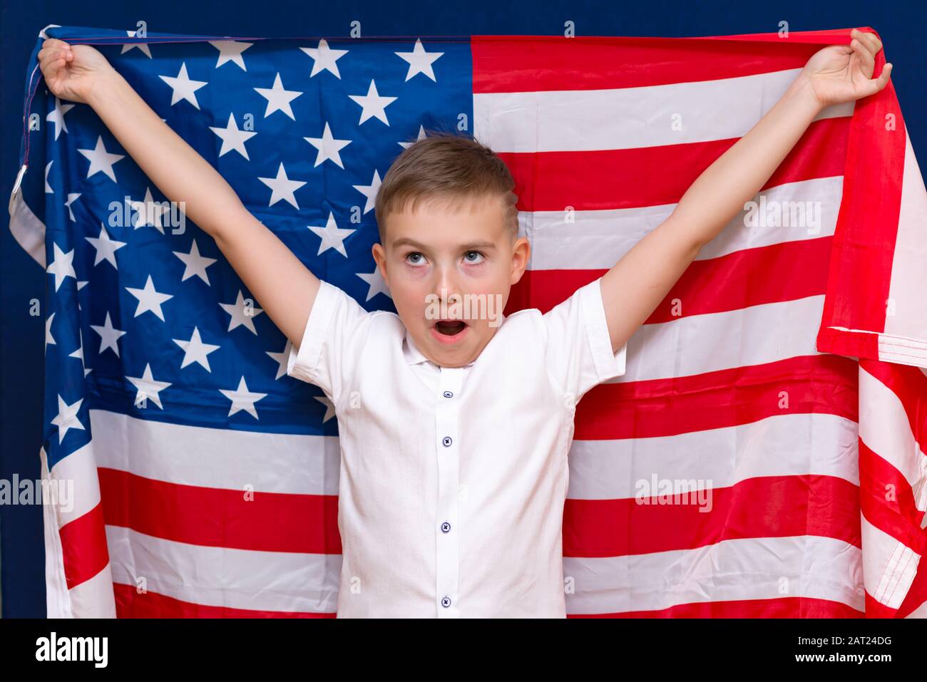 Boy hält eine USA-Flagge über blauem Studiohintergrund. Stockfoto