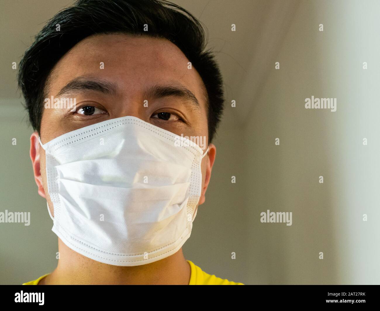 Nahaufnahme des asiatischen Chinesen, der eine chirurgische Gesichtsmaske trägt, als Schutz vor Übertragung/Infektion ansteckender Viren mit Stockfoto