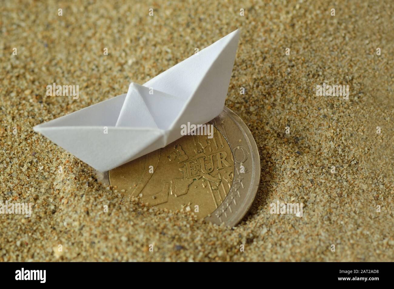 Papierboot und Euro-Münze auf dem Sand - Konzept der Einwanderung Stockfoto