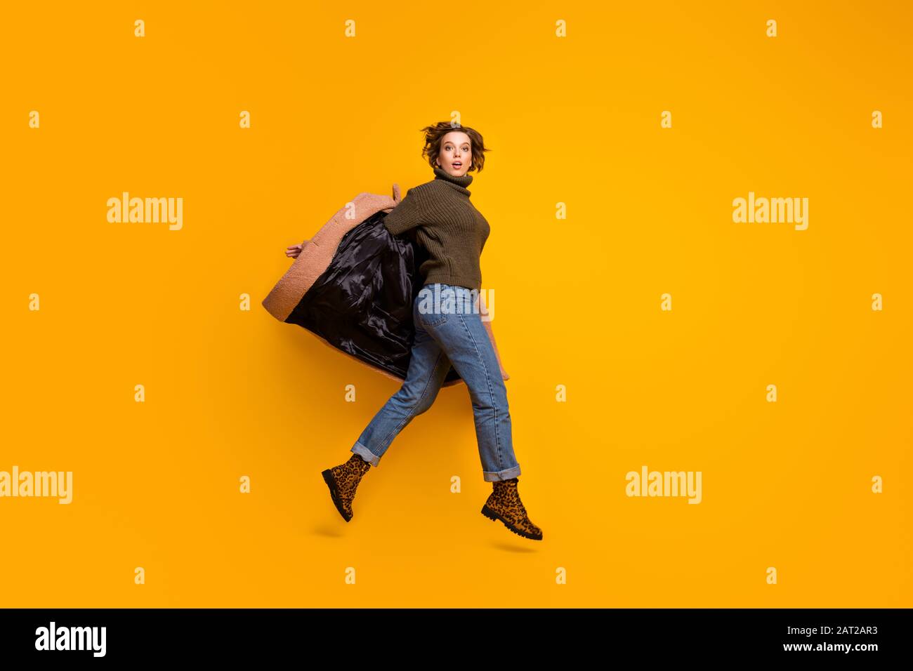 Ganzkörperprofil Foto von lustiger hübscher Dame, die in einem Einkaufszentrum mit hohem Gehweg aufspringt und einen legeren pinkfarbenen Mantel auszieht, tragen gestrickte Pullover Jeans Leopard Stockfoto