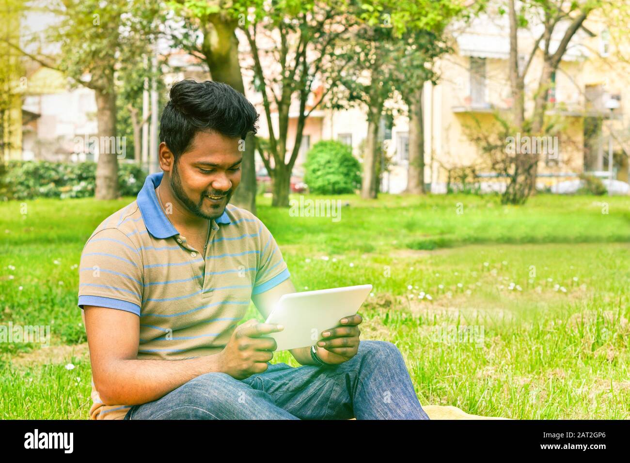 Junger indianermann hat Videoaufruf auf Tablet im Park University Camp - Konzept der neuen Technologie Wundersucht - weicher, warm gesättigter Filter Stockfoto