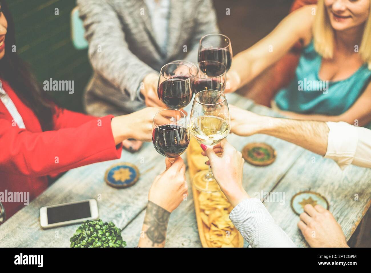 Trendige Freunde jubeln mit Wein in einer Vintage-Bar - Junge glückliche Leute haben Spaß am Partyabendessen - Freundschafts- und Jugendkonzept - Stockfoto