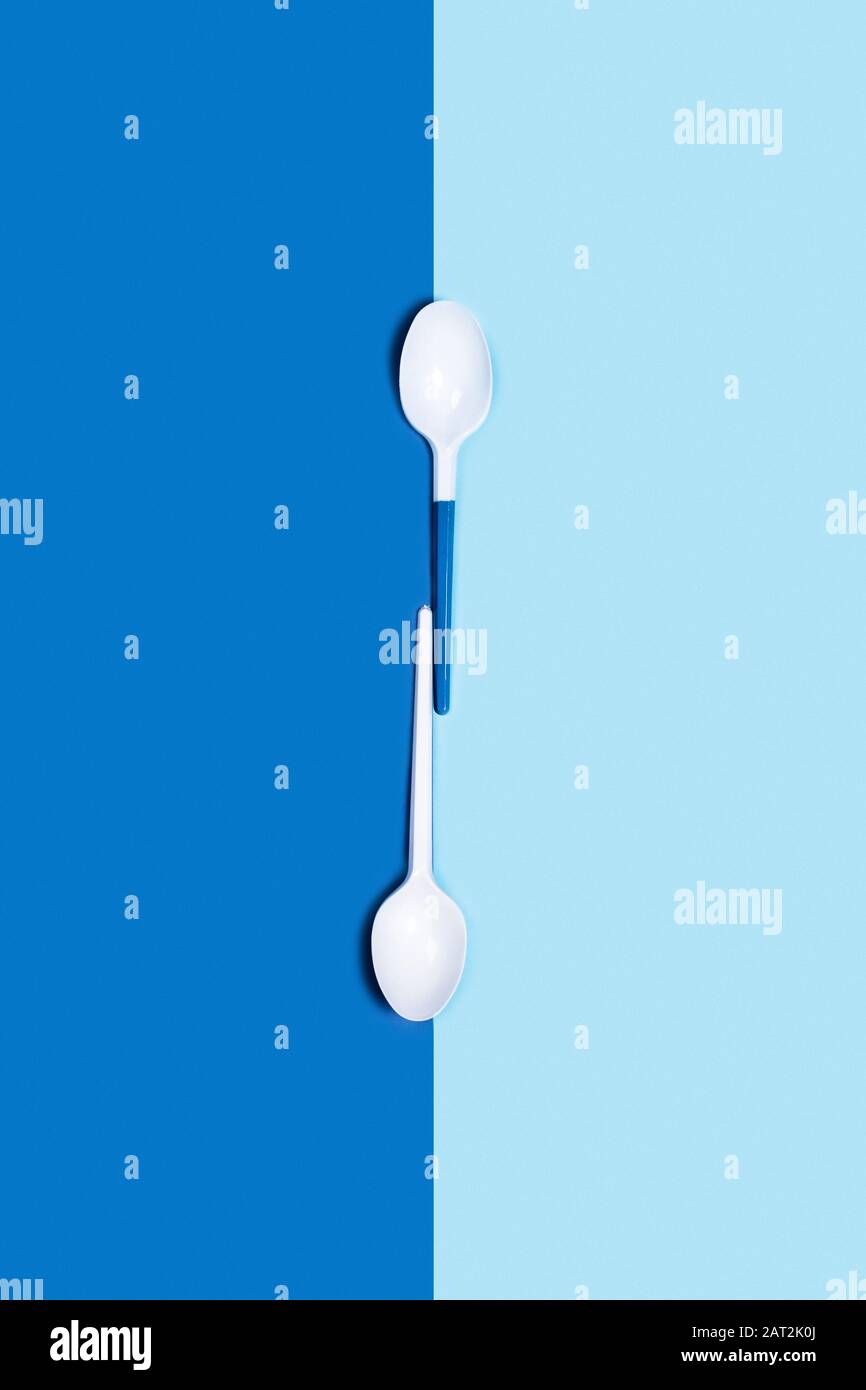 Abbildung der weißen Kunststofflöffel auf zweigezungtem blauem Hintergrund. Flache Lage, Draufsicht. Flaches Layout, Draufsicht, Kopierbereich. Stockfoto