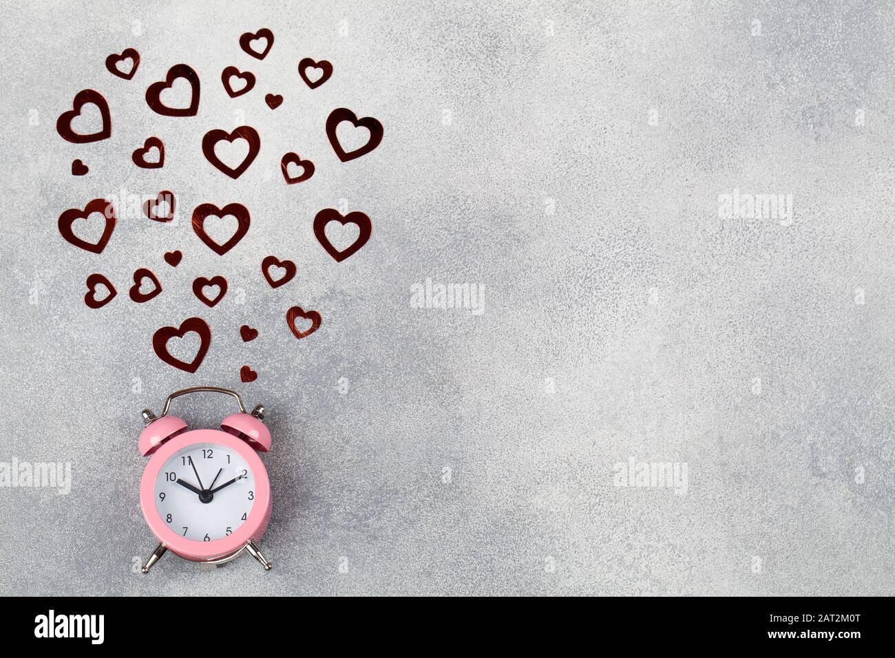 Zeitkonzept Wecker in blauem Hintergrund mit rotem Herz. Minimalistischer Stil. Platz für Text. Valentinstag Hintergrund. Designelement für Begrüßung Stockfoto