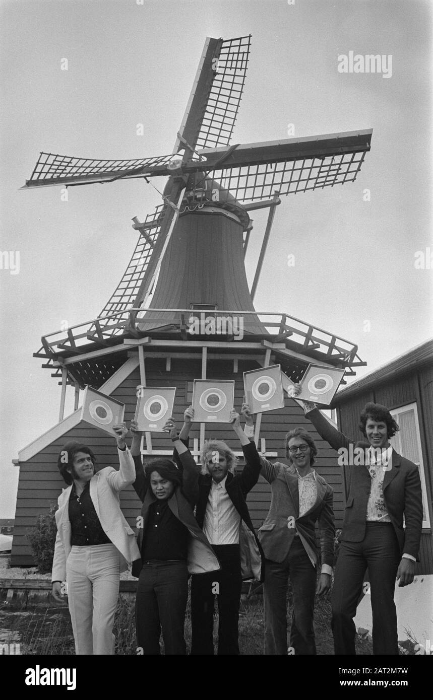 Die Zaanse Popgruppe The George Baker Selection erhält auf der Zaanse Schans eine goldene Schallplatte für Little Green Bag (1 Million Exemplare). Vor dem Hintergrund der Senfmühle De Huisman zeigt die Gruppe seine neu erworbene Trophäe; Stockfoto