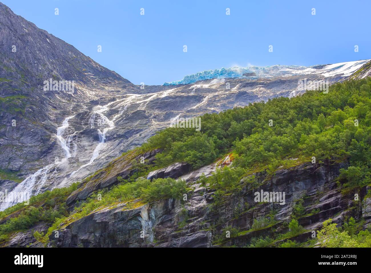 Norwegen, Gletscher mit schmelzendem blauem Eis und Wasserfälle über den Steinfelsen bei Sonnenspiegelungen Stockfoto