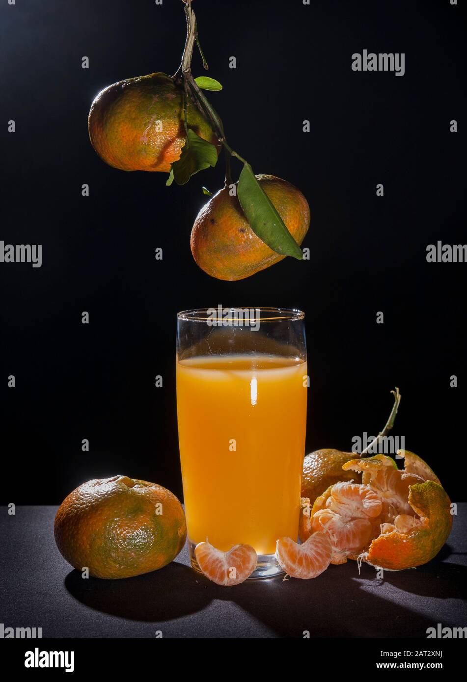 Mandarine und Glas, Zitrus reticula.auf dem Tisch mit schwarzem Hintergrund und Hintergrundbeleuchtung Stillleben.Mandarine Sorte Orange enthält Pomelo und c vi Stockfoto