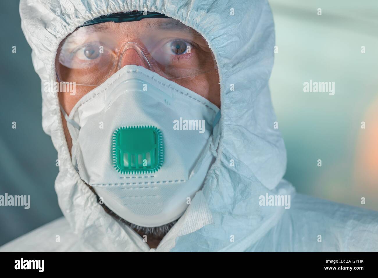 Porträt des männlichen Virologen mit Schutzmaske, Schutzbrille und Kleidung, die auf die Kamera blickt, selektiver Fokus Stockfoto