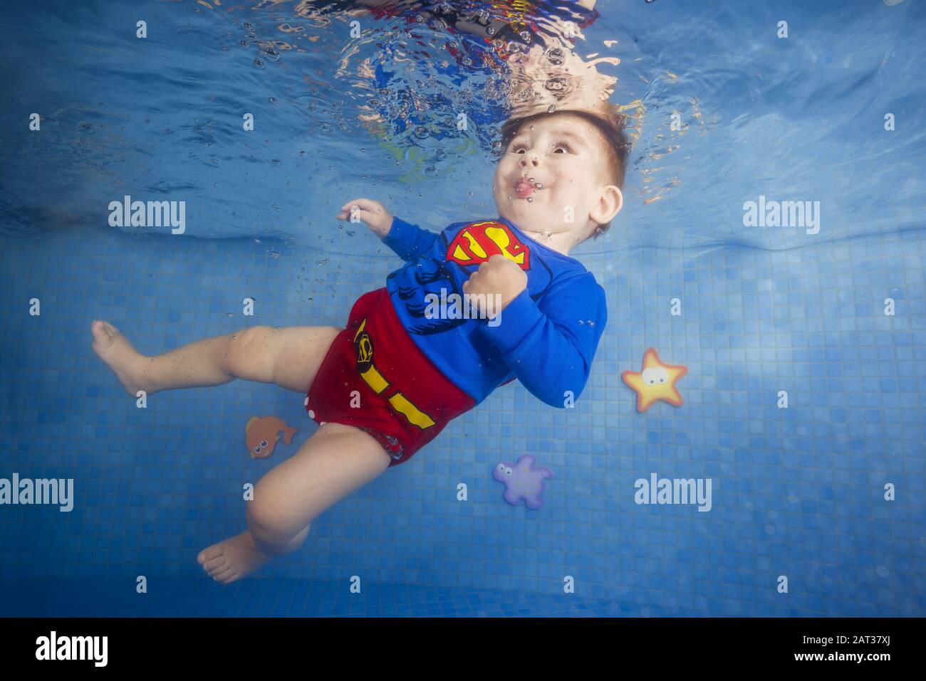 Kleiner Junge in einem Superman-Kostüm taucht unter Wasser im Pool  Stockfotografie - Alamy