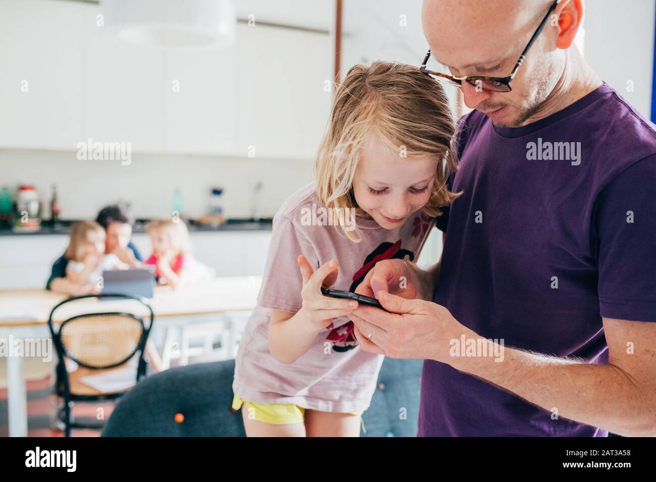 Vater und Tochter im Innenbereich mit Smartphone - Lernen, Unterhaltung, Unterrichtskonzept Stockfoto