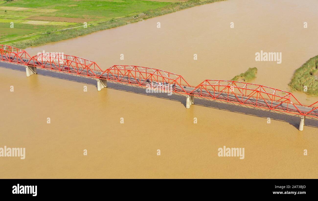 Cagayan River, der nach Volumen größte und der längste Fluss der Philippinen. Die lange Brücke über den Fluss. Autos fahren auf der Brücke, Draufsicht. Stockfoto