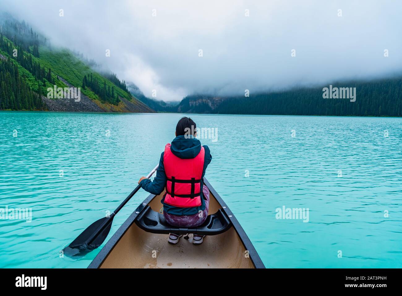 Frau paddelt ein Kanu durch Lake Louise Alberta Kanada Stockfoto