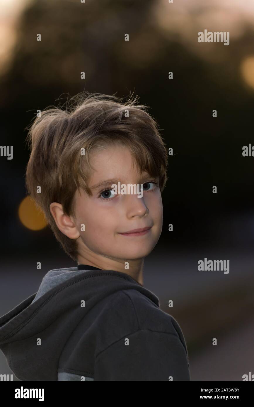 Porträt eines lächelnden Jungen mit verschwommenem Hintergrund in der Abenddämmerung Stockfoto