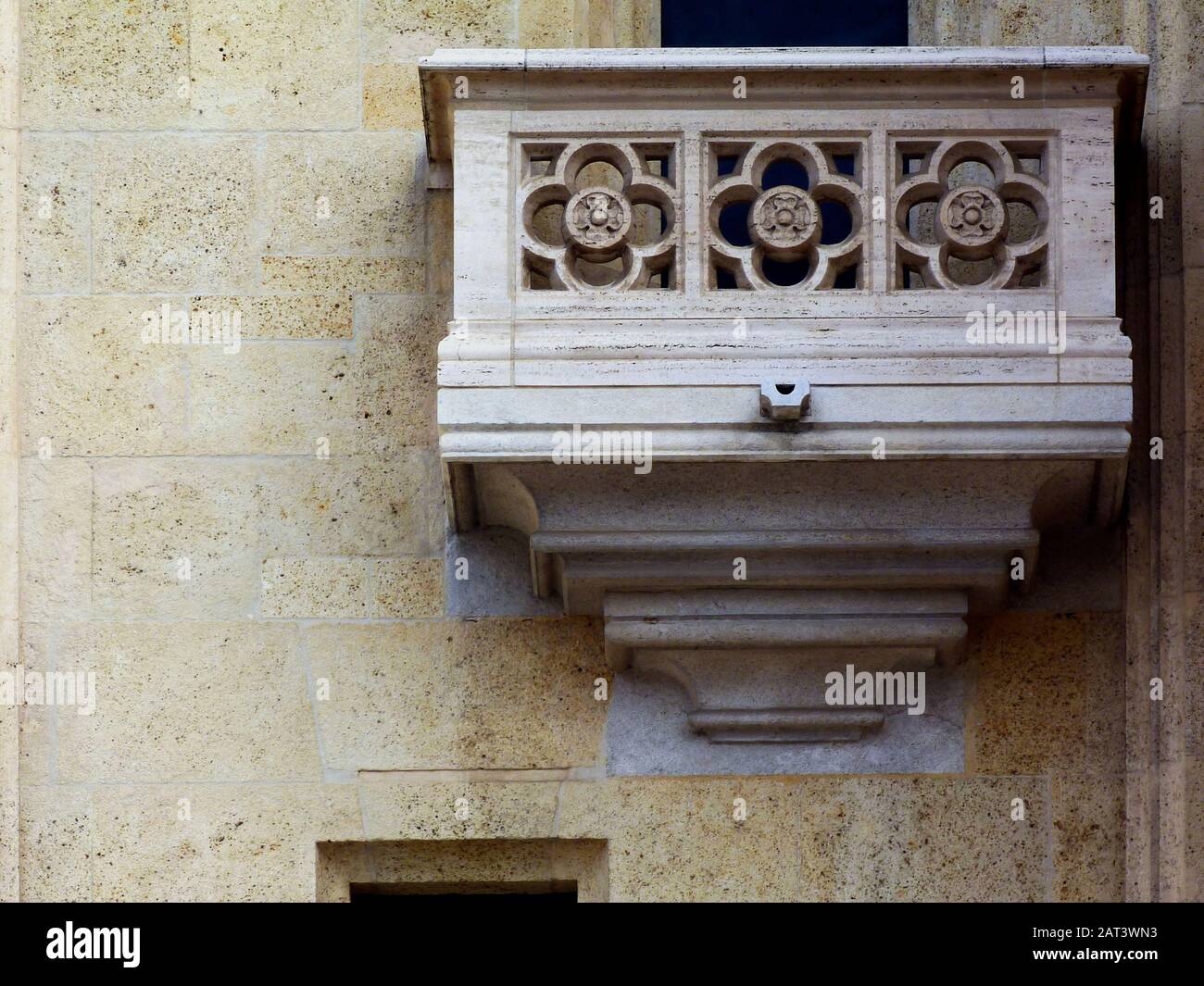 Mit steinernen Lattenarbeiten ausgeformte Außenwand des weißen Gebäudes. Steinerne Balustrade und Balkon in frontaler Höhenansicht. Fassade aus beigefarbenem Stein. Stockfoto