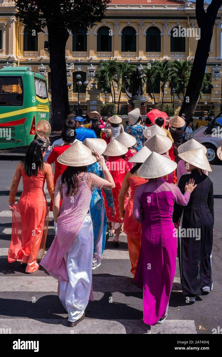 Junge Frauen, die sich in Ao Dai bekleidet haben, überqueren die Straße in Richtung Central Post Office, Ho-Chi-Minh-Stadt, Vietnam Stockfoto Junge Frauen, die sich in Ao Dai bekleidet haben, überqueren die Straße in Richtung Central Post Office, Ho-Chi-Minh-Stadt, Vietnam Stockfoto