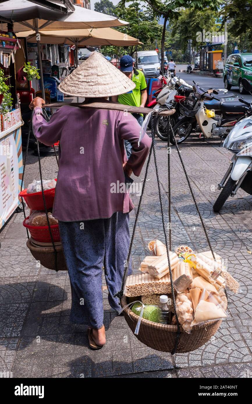 Frau, die einen konischen Hut trägt, der ihren Speisestall entlang der Straße, Ho-Chi-Minh-Stadt, Vietnam, trägt Stockfoto
