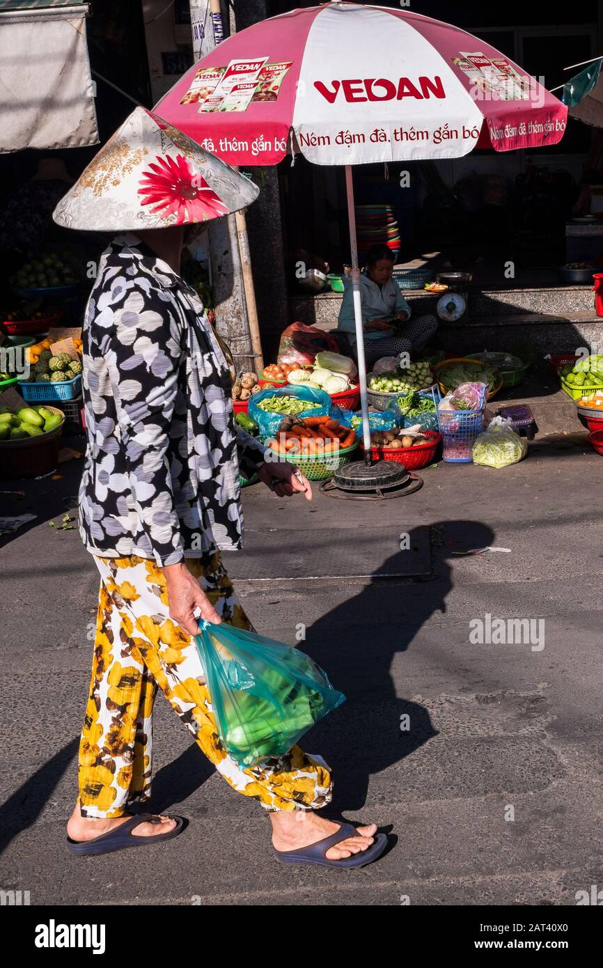 Frau, die in Plastiktüten einkaufen geht, die durch den Straßenmarkt geht, Ho-Chi-Minh-Stadt, Vietnam Stockfoto