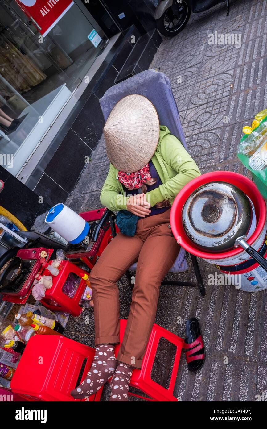 Frau Straßenverkäuferin schläft unter konischem Hut, Ho-Chi-Minh-Stadt, Vietnam Stockfoto