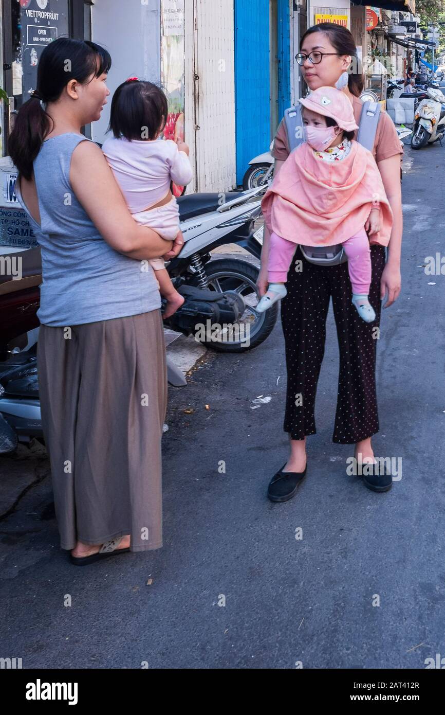 Frauen, die Kinder auf der Straße unterhalten, Ho-Chi-Minh-Stadt, Vietnam Stockfoto