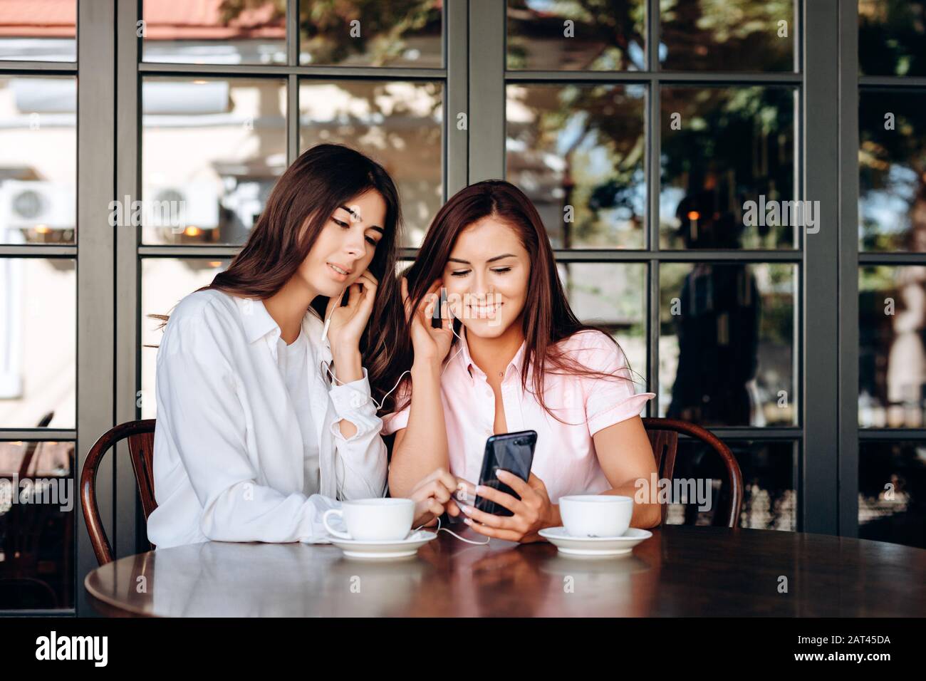 Lächelnde Geschäftsfrauen hören wichtige Funktionsstörungen der Kopfhörer. Stockfoto