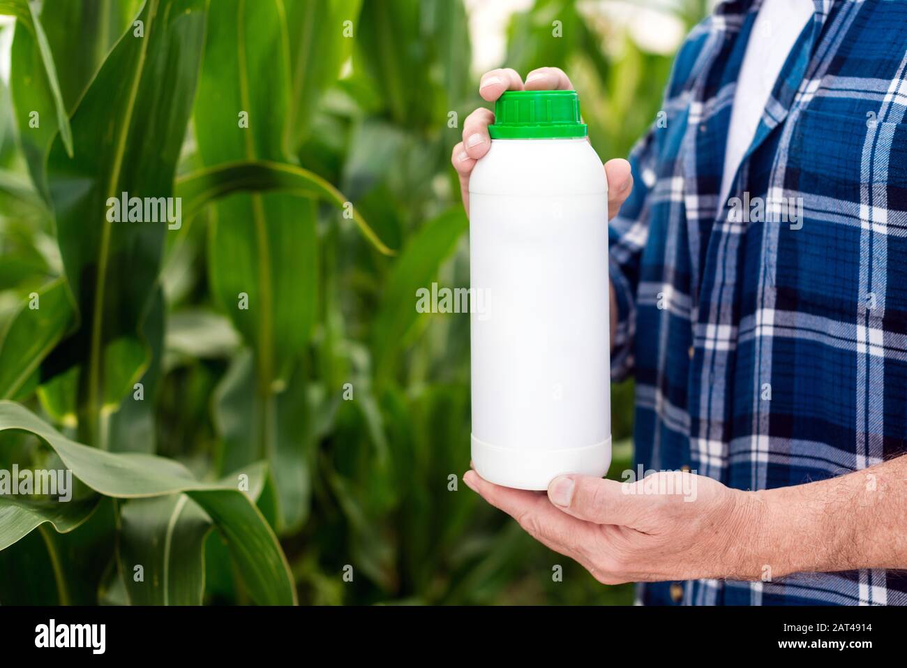 Nahfüllflasche in den Händen des Landwirts. Leere, unbeschriftete Flasche als verspotteten Kopierraum für Herbizid, Fungizid oder Insektizid Stockfoto