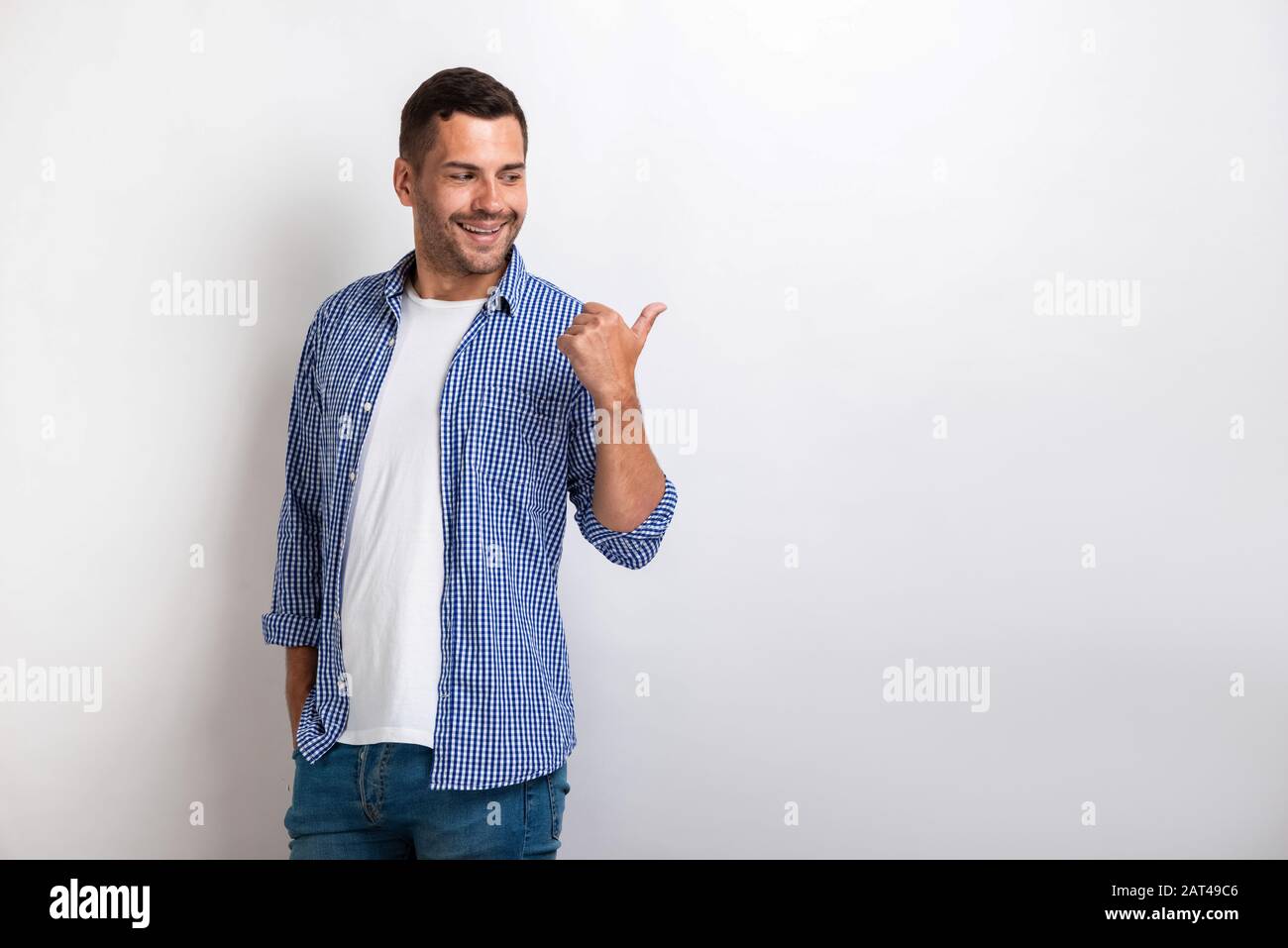 Gutaussehender glücklicher Mann, der mit seinem großen Finger seitlich zeigt.- Bild Stockfoto