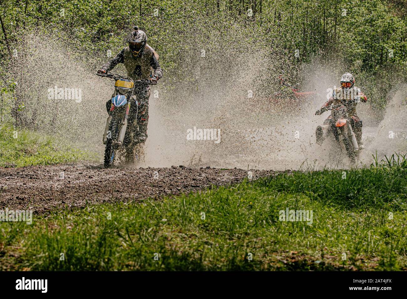 Zwei Motorradfahrer, die auf Wasser- und Schlammwegen fahren Stockfoto
