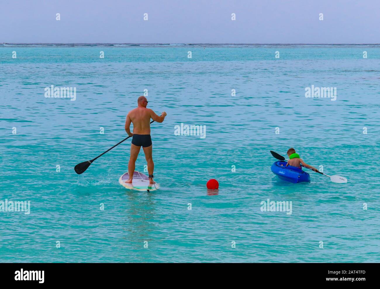 Vater und Sohn genießen Wassersport auf den Malediven. Vater paddleboarding und das Kind Kajak von einer Insel im South Ari Atoll Stockfoto