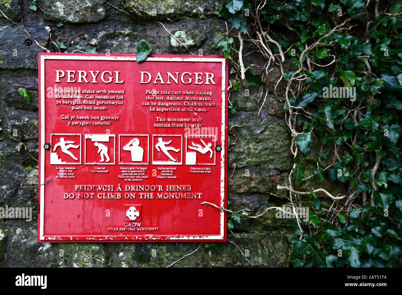 Melden Sie sich in walisischer und englischer Sprache an, und warnen Sie, nicht auf Steinmauern, Coity Castle, Mid Glamorgan, Wales, Großbritannien zu klettern Stockfoto
