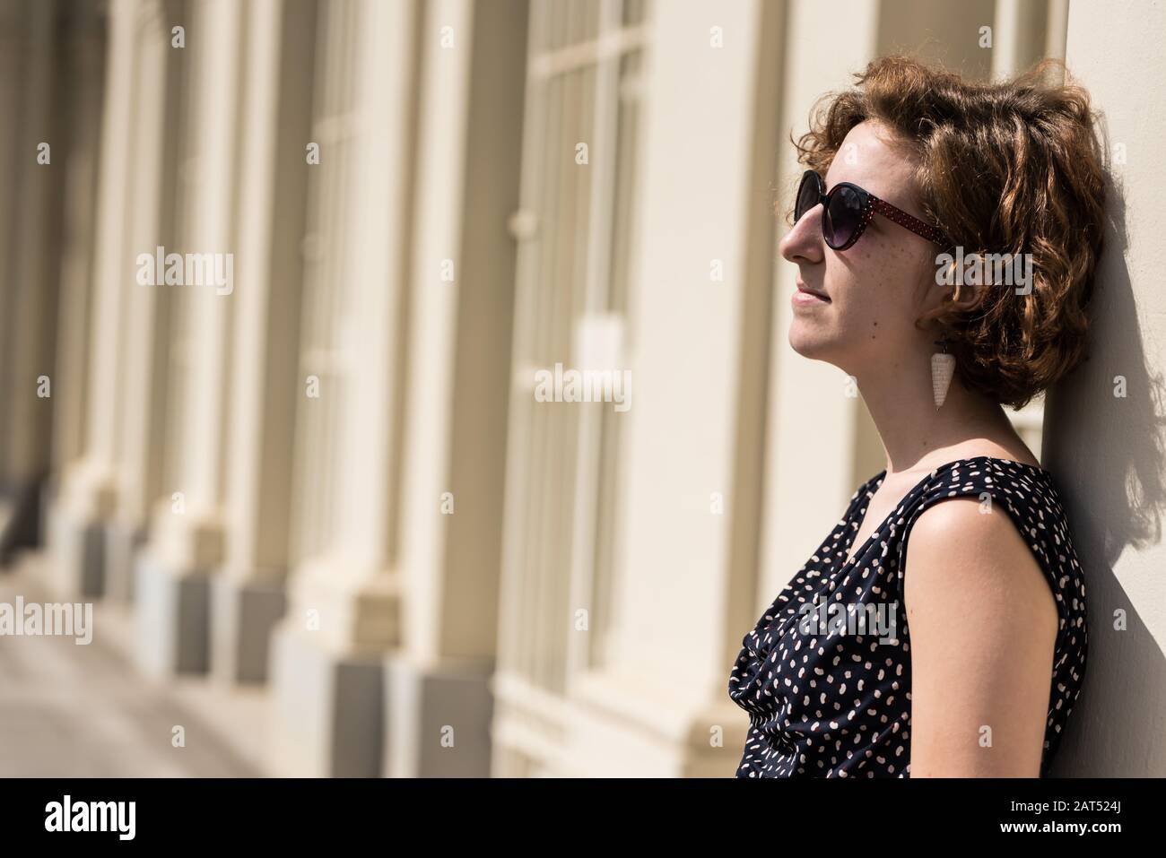Porträt eines zwanzigjährigen Mädchens nebenan mit Sonnenbrille in der Stadt Stockfoto
