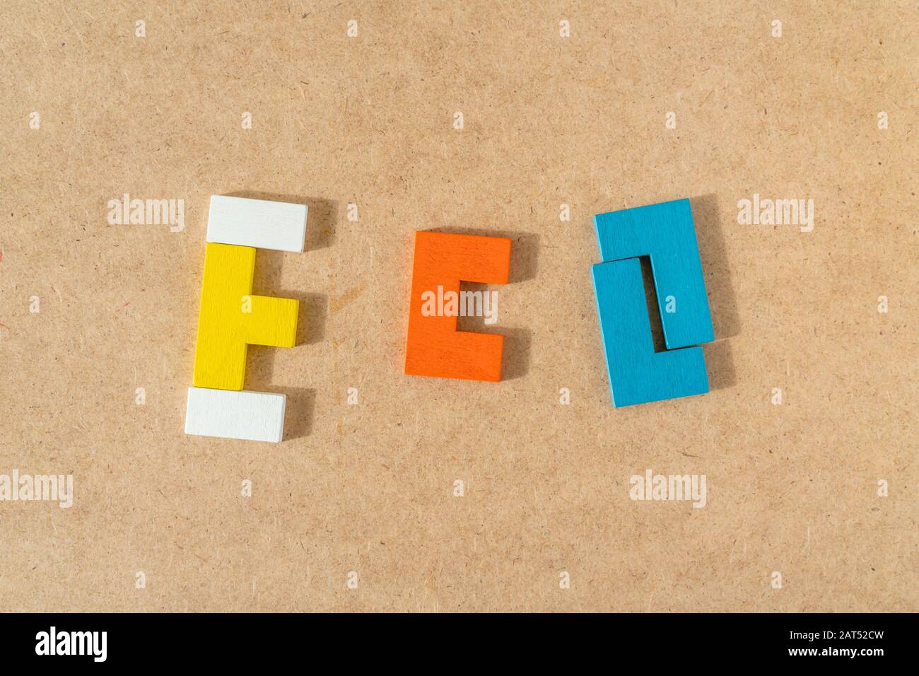 Word ECO aus bunten Holzziegeln auf KRAFT-Kartonhintergrund. Draufsicht, flacher Lay. Stockfoto