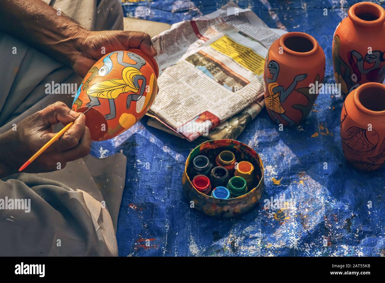 Ein männlicher Künstler, der Stoffbemalung auf handgefertigten Kunsthandwerksartikeln zu einem Kunsthandwerkstarif in Kolkata, Indien, macht Stockfoto