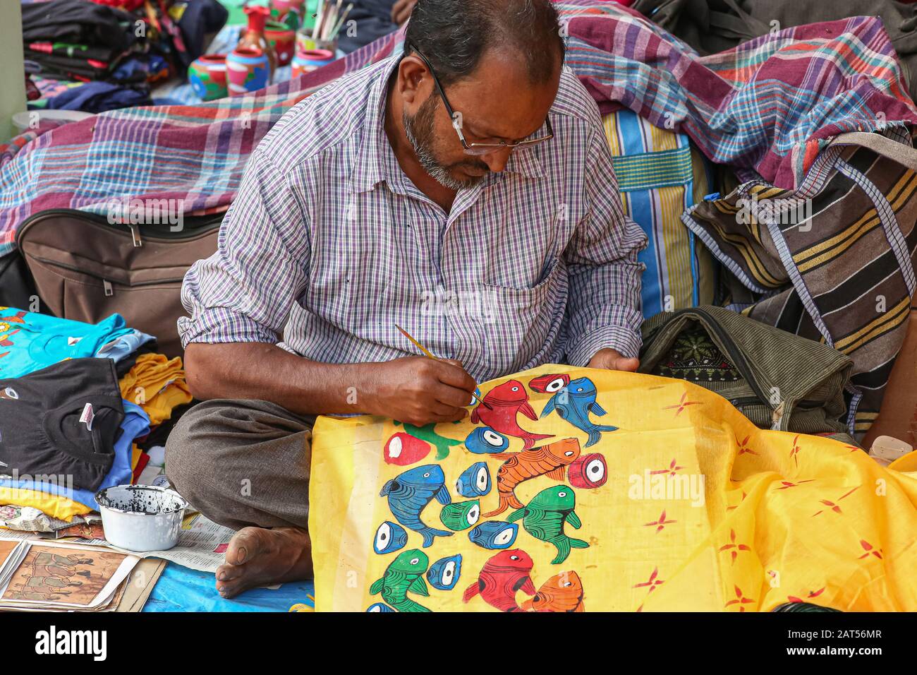 Ein männlicher Künstler, der Stoffbemalung auf handgefertigten Kunsthandwerksartikeln zu einem Kunsthandwerkstarif in Kolkata, Indien, macht Stockfoto